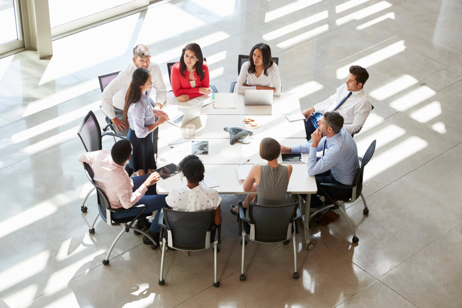 Businesswoman addressing colleagues at table, elevated view